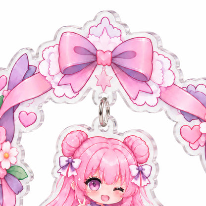 A close-up of a hanging acrylic "wobbler" stand featuring a wreath design, alongside a custom acrylic stand printed with a chibi-style anime character.