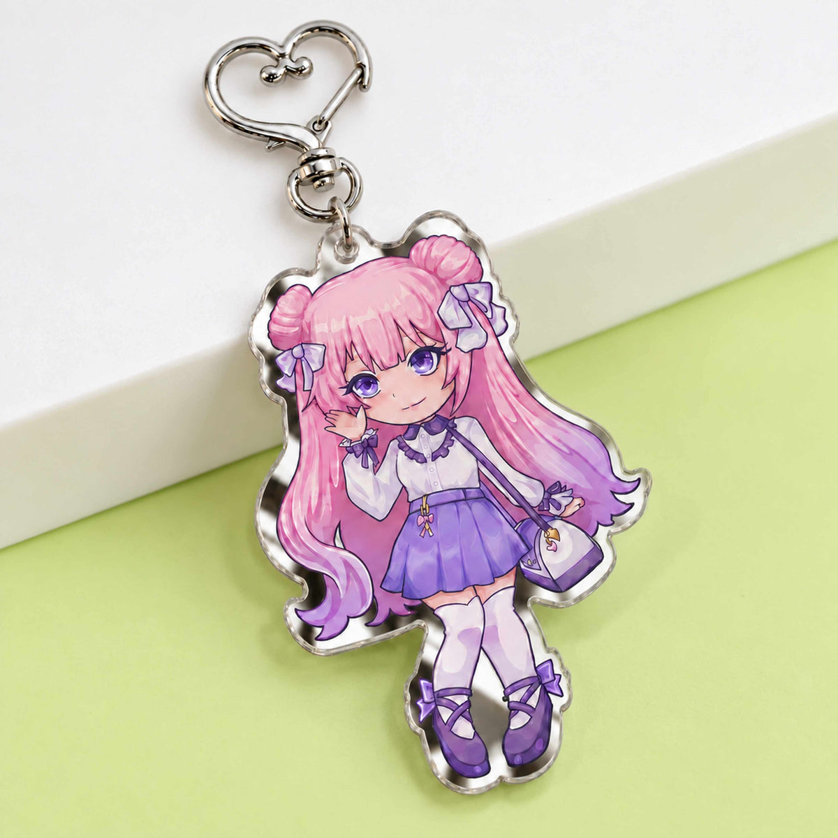 Anime chibi girl mirror acrylic keychain displayed on light green table, custom printed die cut mirror acrylic charm