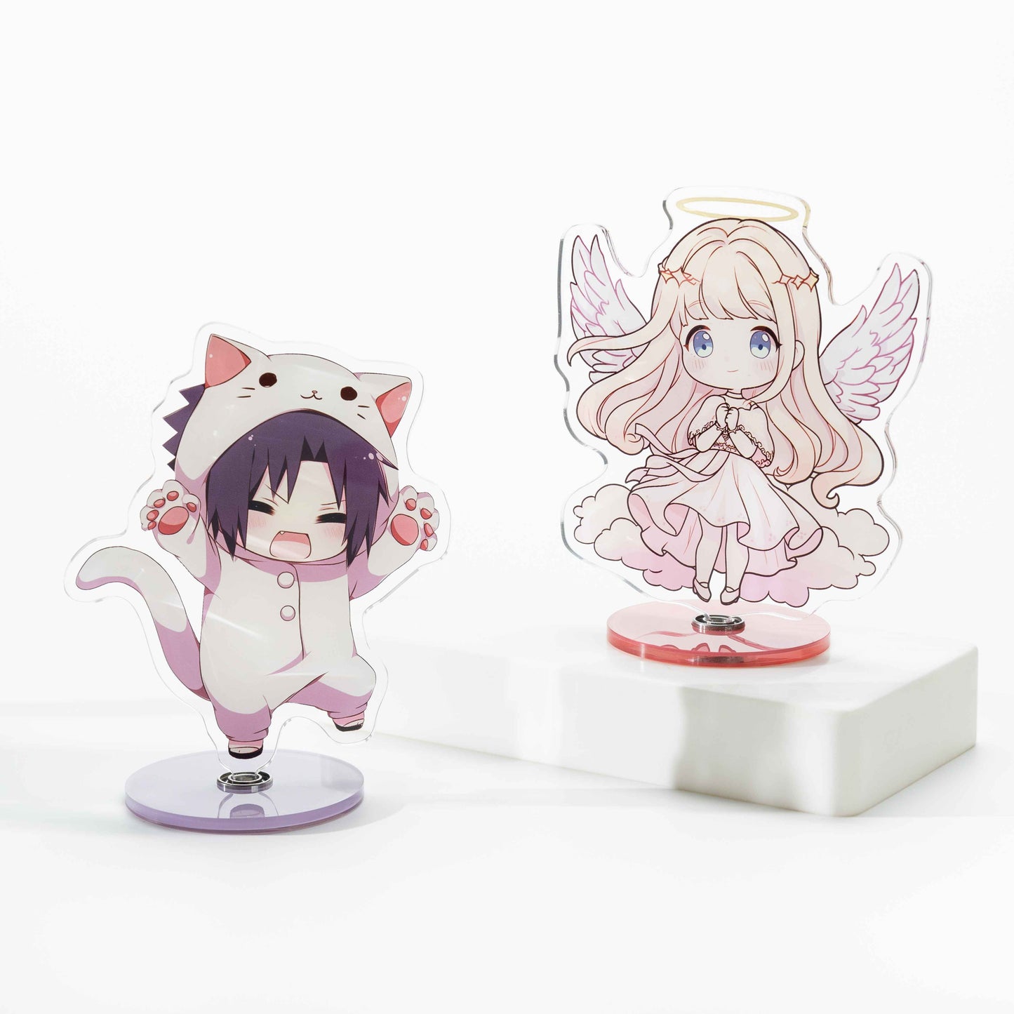 Two custom rotating acrylic standees: desktop ornaments featuring anime-style characters—a chibi boy in a cat onesie and an angel girl.