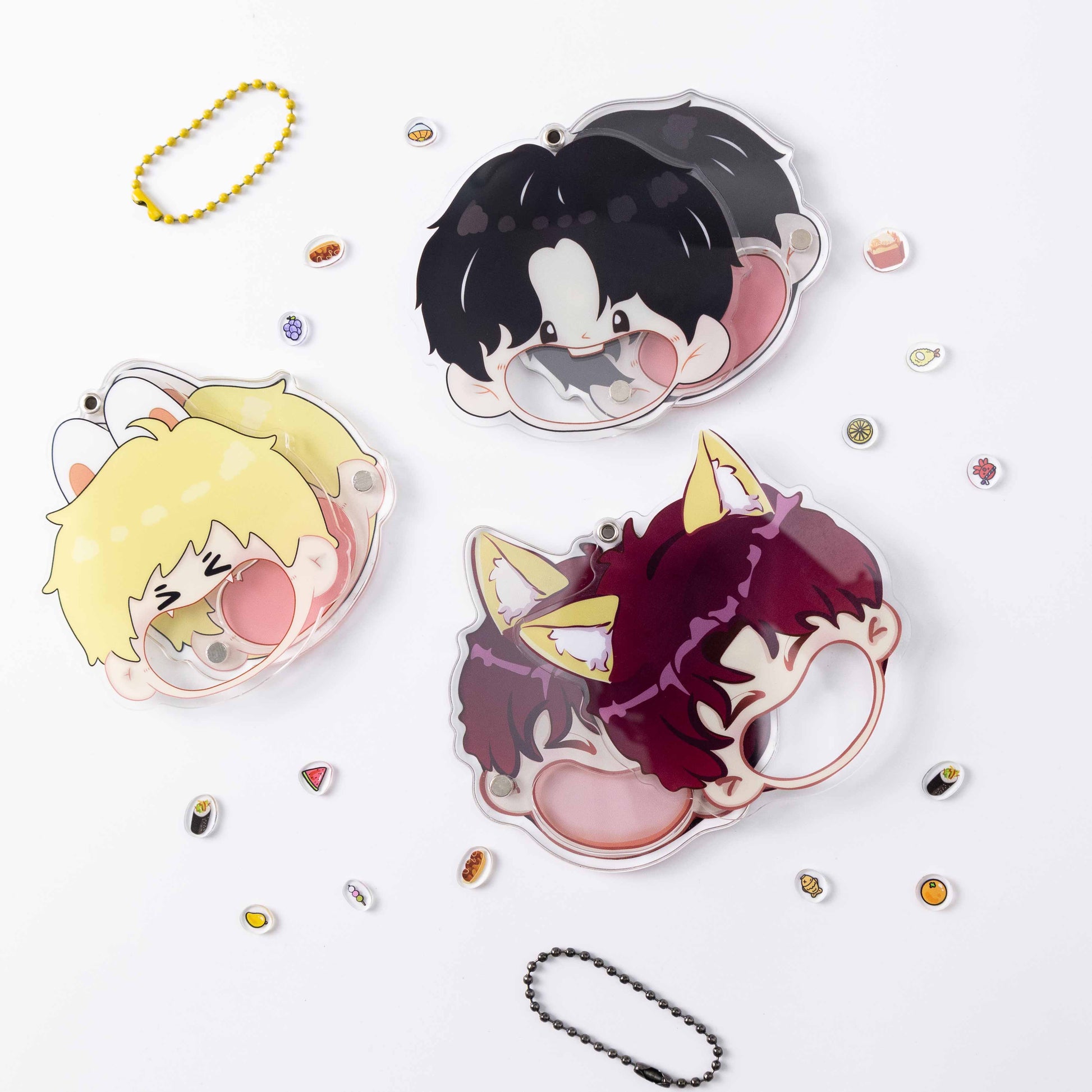 Three different cartoon characters are featured on the acrylic keychain shells, with food accessories and beaded cords scattered around them.